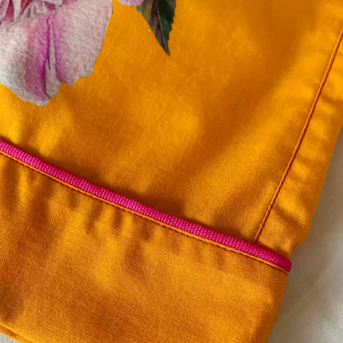Detalhe do acabamento do shorts e da calça do pijama Naps, com vivo e pesponto na estampa Tropicália