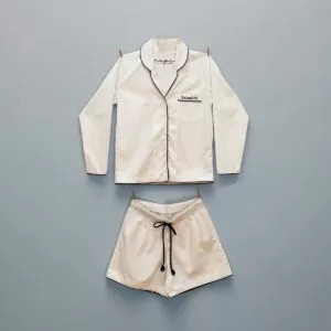 Conjunto pijama feminino Naps liso na cor Cru, em tecido 100% algodão com toque acetinado e modelagem solta, composto por camisa manga longa e shorts