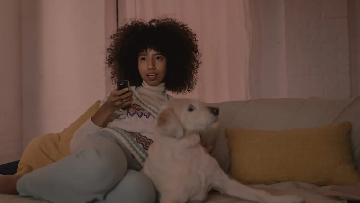 Mulher assistindo TV à série antes de dormir à noite no sofá com um cachorro deitado ao lado