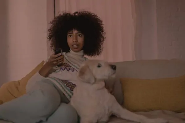Mulher assistindo TV à série antes de dormir à noite no sofá com um cachorro deitado ao lado