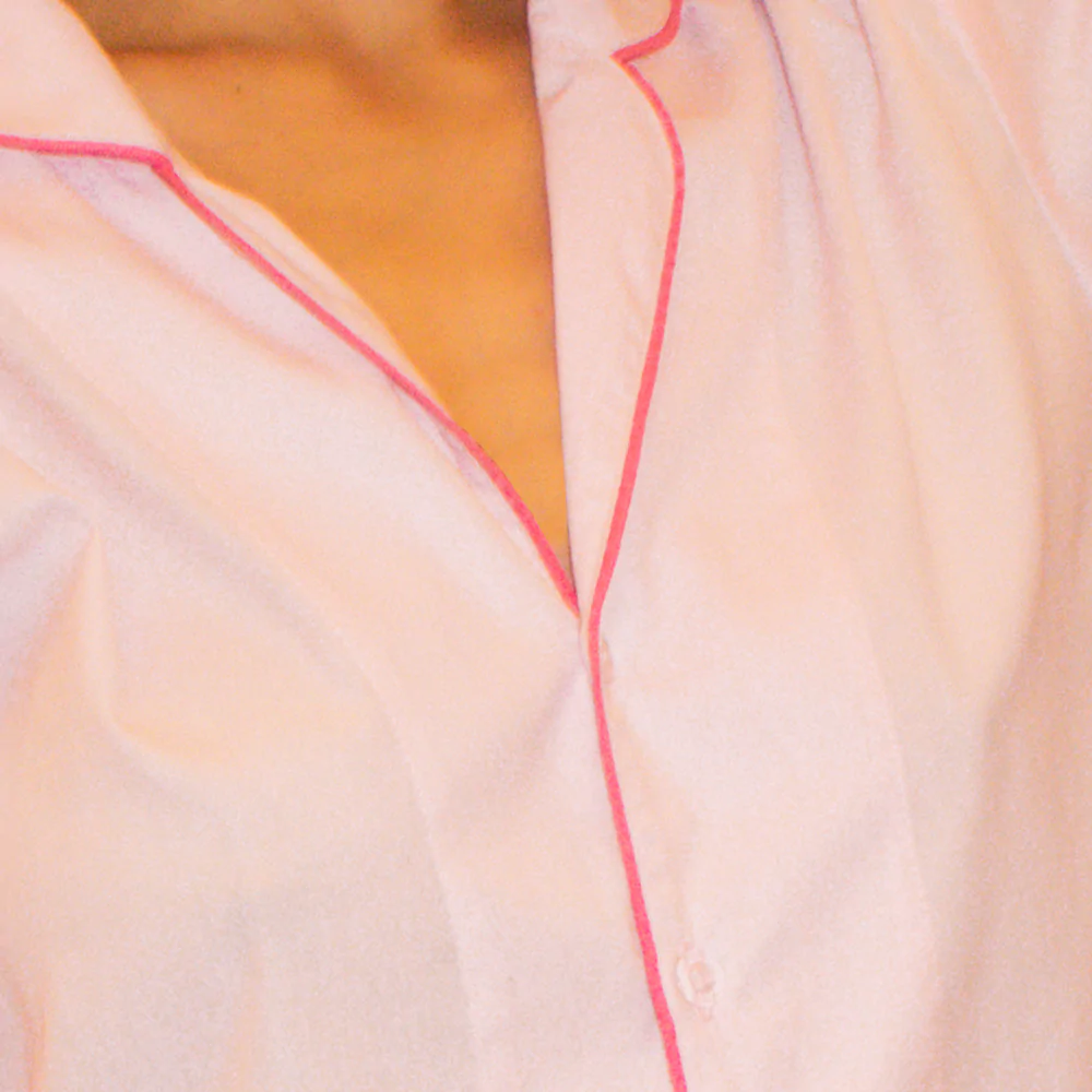 Detalhe do pijama rosa bebê da Naps com acabamento pink, mostrando a gola e o vivo contrastante em tecido 100% algodão.