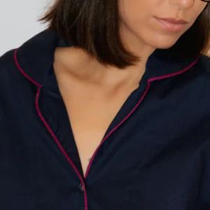 Mulher usando pijama personalizado azul bebê de manga curta e shorts, em tecido 100% algodão com acabamento azul-marinho, encostando o rosto em uma almofada floral.