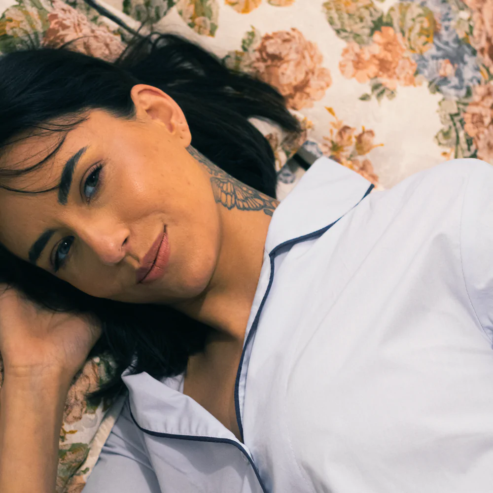 Mulher deitada usando pijama personalizado azul bebê com acabamento azul-marinho, em tecido 100% algodão.