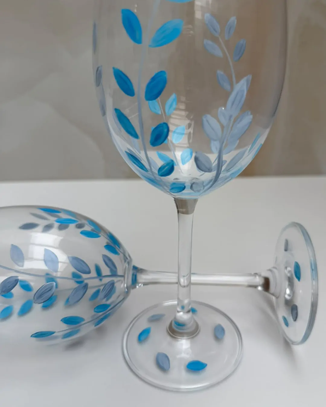Detalhe da pintura à mão com folhas azuis nas taças de cristal Azul Silencioso da Naps