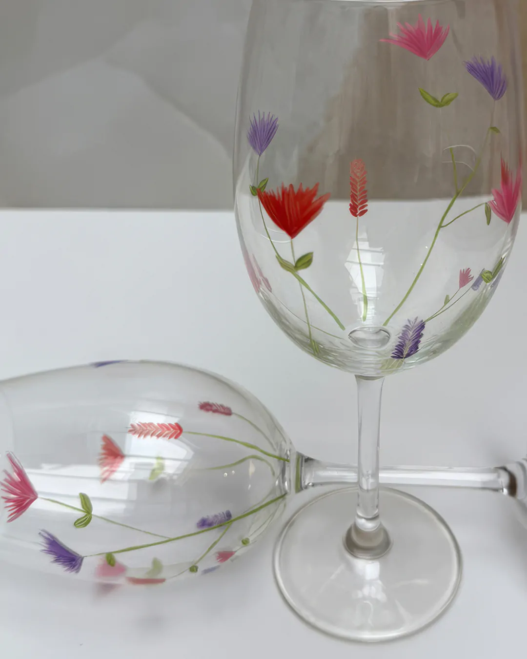 Detalhe de taças de cristal pintadas à mão com flores coloridas, estampa Doce Jardim da Naps